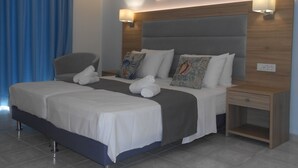 A modern hotel room with a double bed, two bedside tables, a chair, and artwork on the walls. - Aristo (Hersonissos)