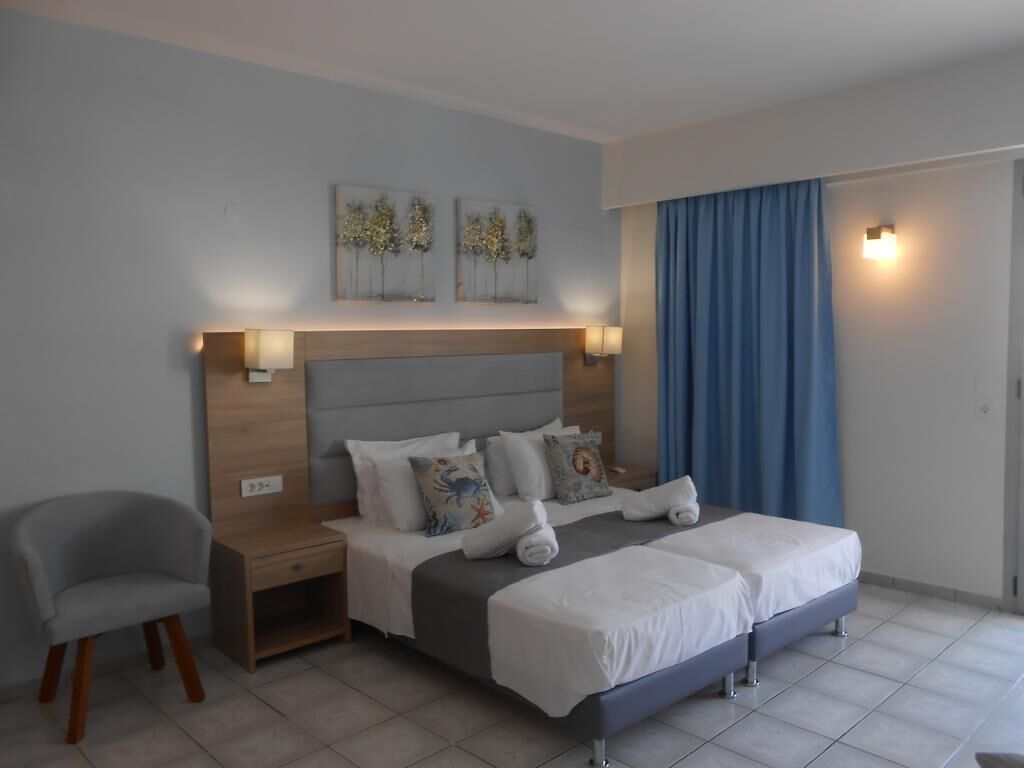A hotel room with a double bed, two bedside tables, a chair, and artwork on the wall.