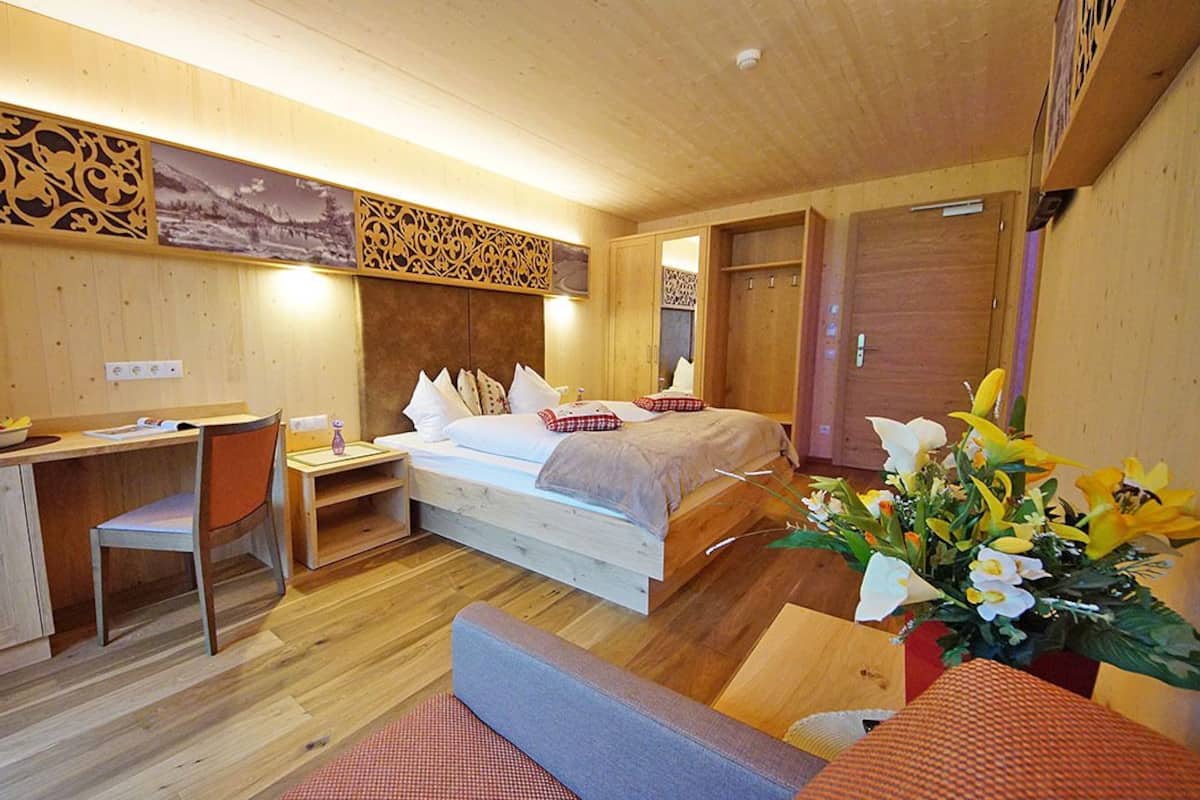Ein Zimmer aus Holz mit einem Bett, einem Schreibtisch, einem Stuhl und einem kleinen Tisch mit einer Obstschale.