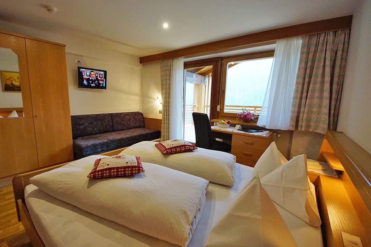 Ein Hotelzimmer mit zwei Betten, einer Couch, einem Schreibtisch und einem Fernseher.