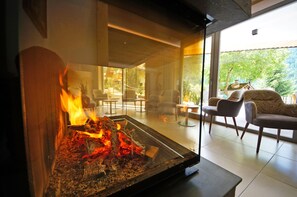 Een moderne woonkamer met een glazen haard, comfortabele zitplaatsen en uitzicht op het omliggende landschap.