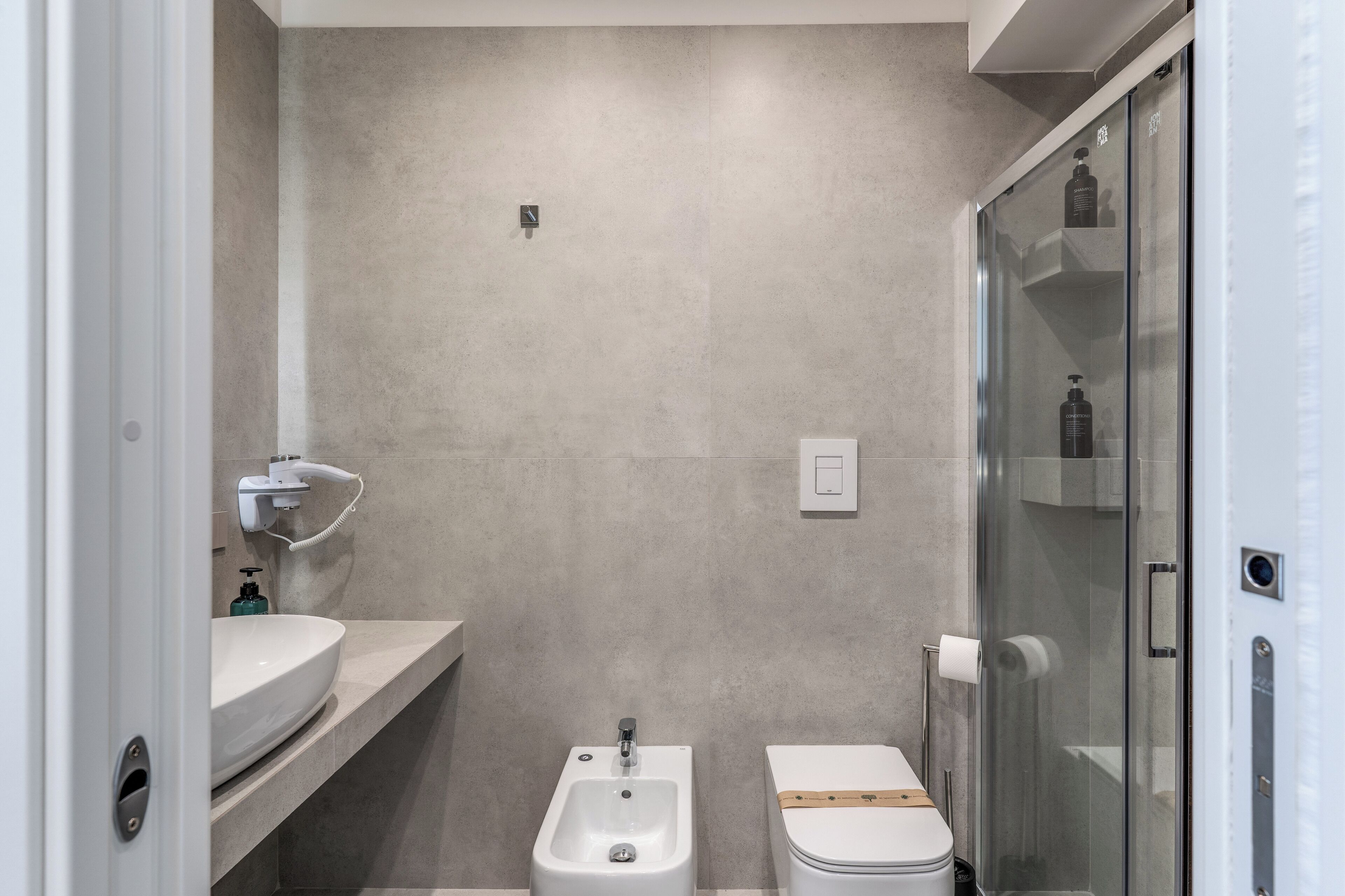 A modern bathroom with a bidet, toilet, and glass shower enclosure.