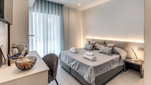 A modern hotel room with a bed, bedside table, and a desk with a bowl of bread. - B&B Welcome Inn Napoli (Naples)