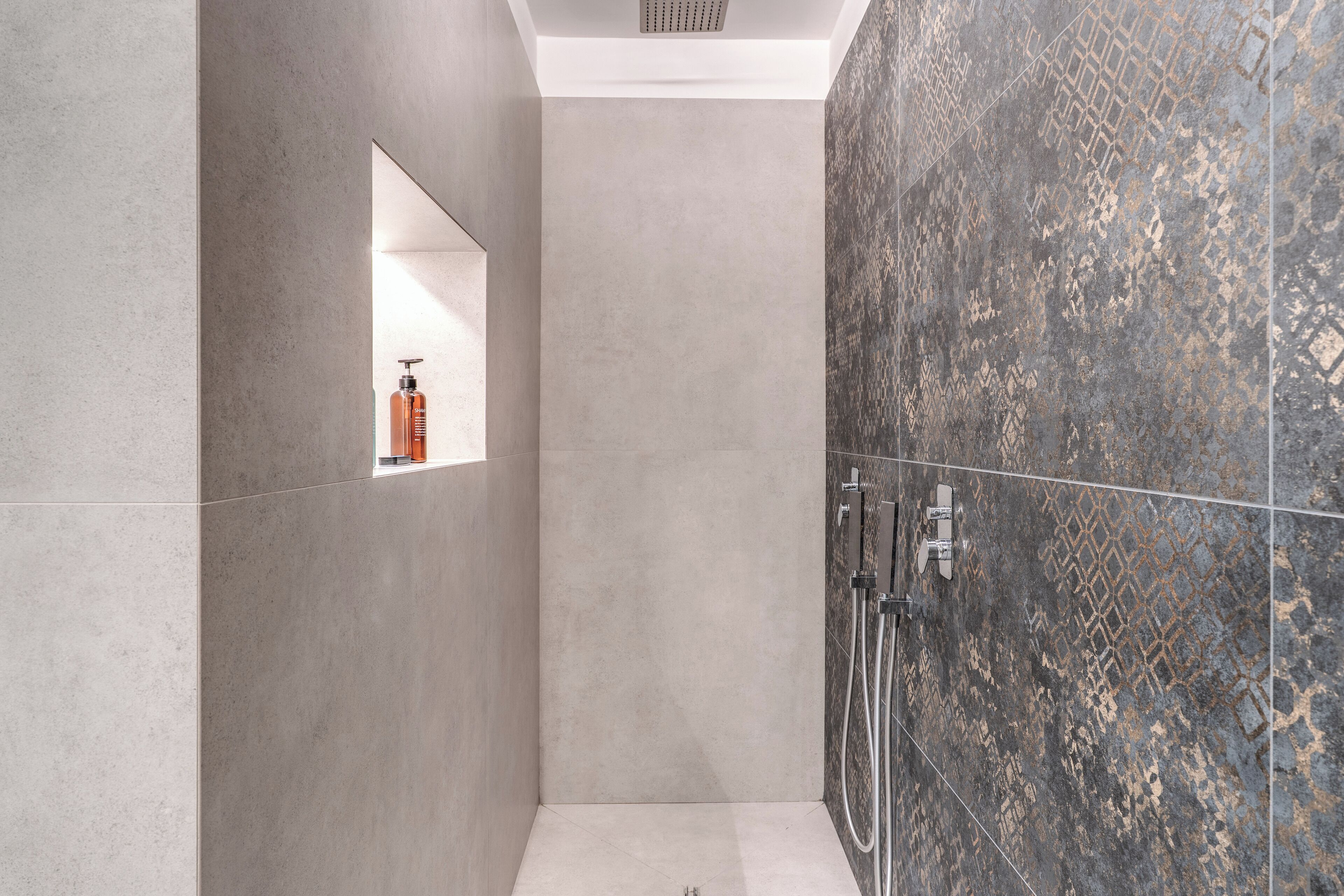 A modern bathroom with a shower, a small mirror, and a shelf with toiletries.