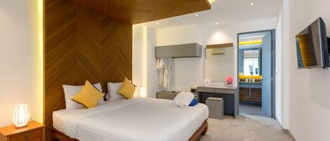 A modern hotel room with a large bed, bedside table, and a desk with a chair.