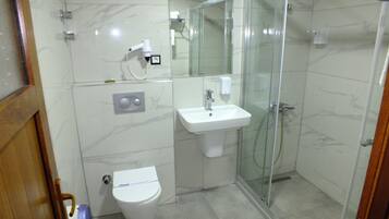 Un baño moderno con inodoro, lavabo y cabina de ducha con mampara de vidrio.