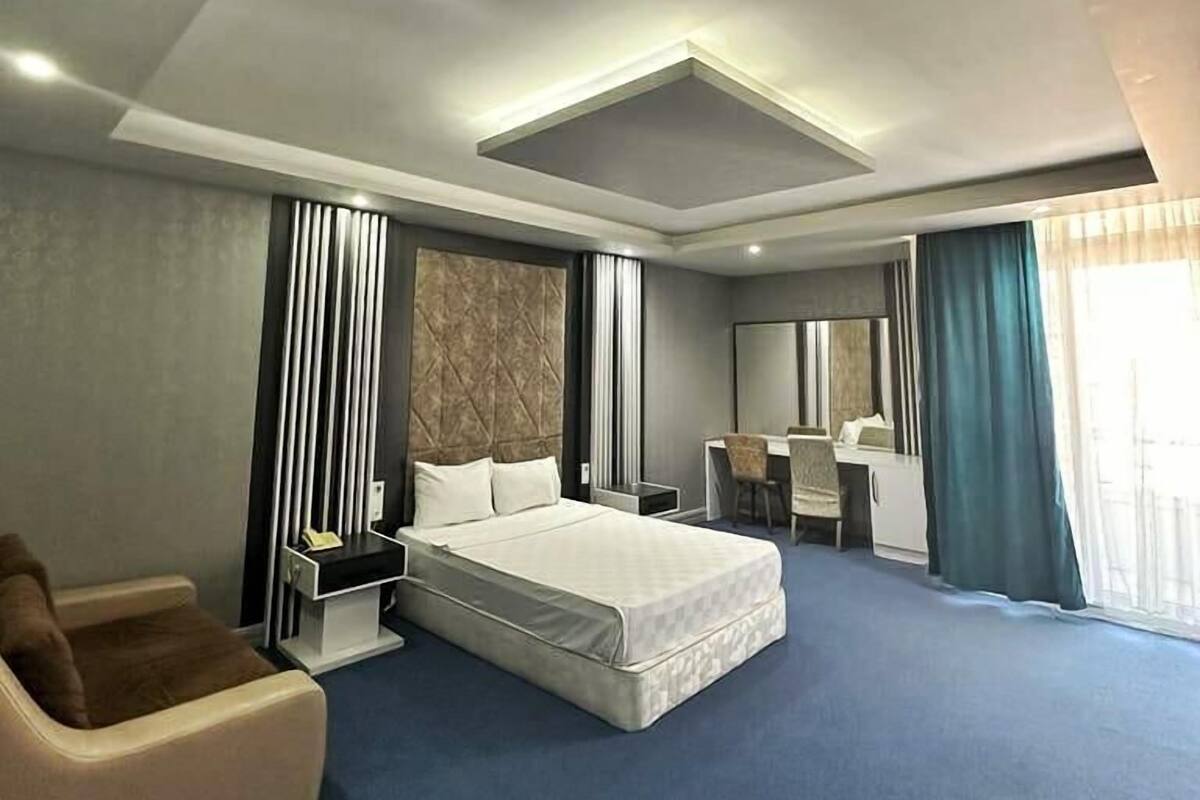 A modern hotel room with a large bed, a desk, and a chair.