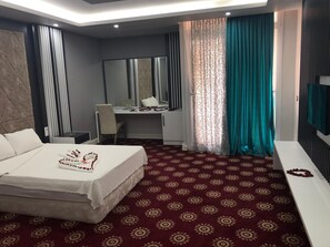Una habitación de hotel con cama, escritorio, silla, espejo y televisión.