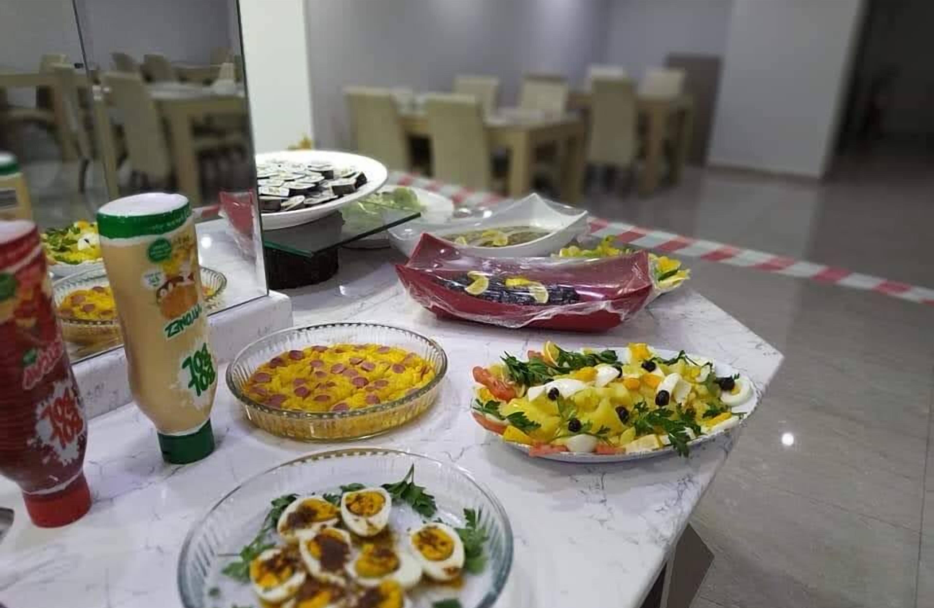A buffet table with various dishes, including salads, a casserole, and a dish with eggs and vegetables.