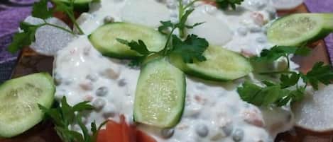 A plate of food with sliced cucumbers, carrots, and a dollop of creamy sauce, garnished with parsley.