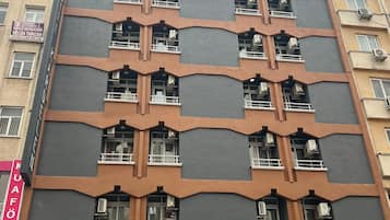Ein mehrgeschossiges Gebäude mit markanter Architektur, das eine Reihe von Balkonen und große Fenster aufweist.