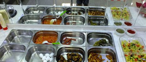 A buffet with various food items and condiments.