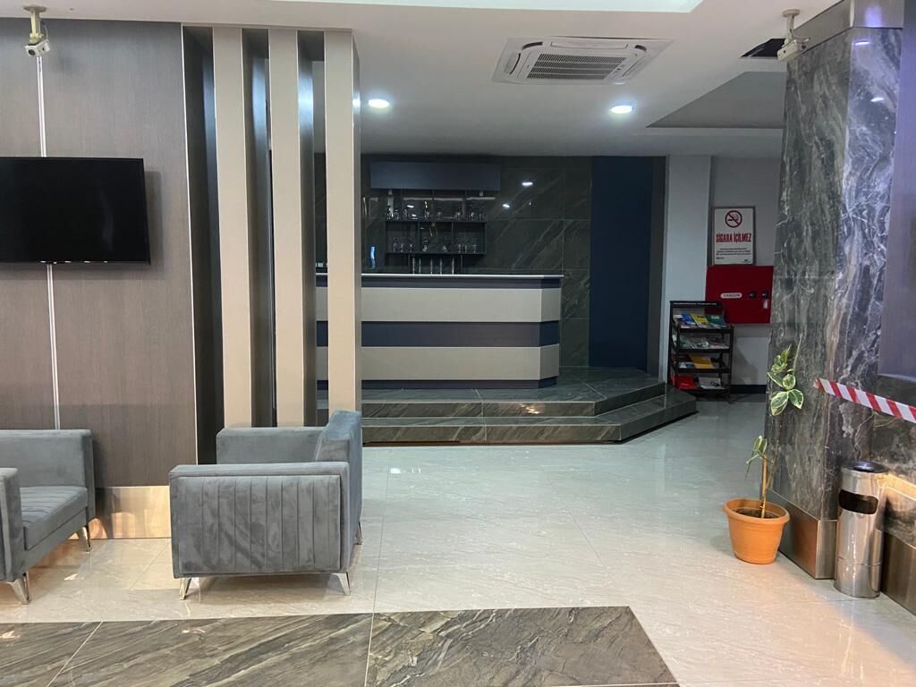 A lobby with a reception desk, seating area, and a potted plant.