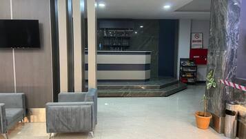 A lobby with a reception desk, seating area, and a potted plant.