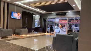 Un vestíbulo moderno con suelo de mármol, área de descanso y una pantalla de televisión.