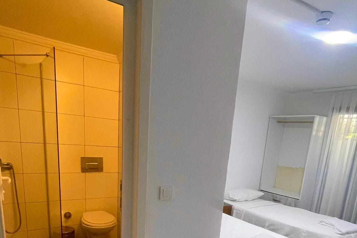 Hotellihuone, jossa on kylpyhuone, suihku, kaksi sänkyä ja peili.
