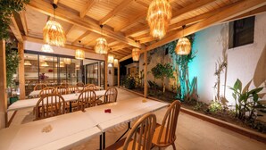 Un espace repas avec des tables et des chaises en bois, des luminaires suspendus et une fresque murale.