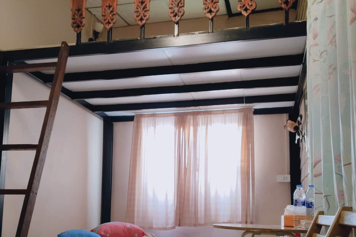 A bunk bed room with a ladder, a small table, and a window with curtains.