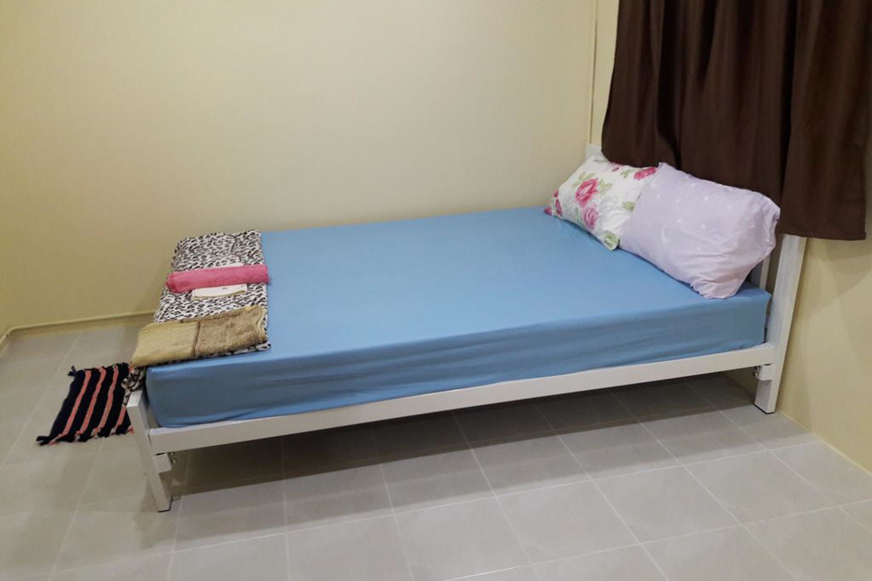 Un lit simple avec un matelas bleu, deux oreillers et une couverture à rayures.