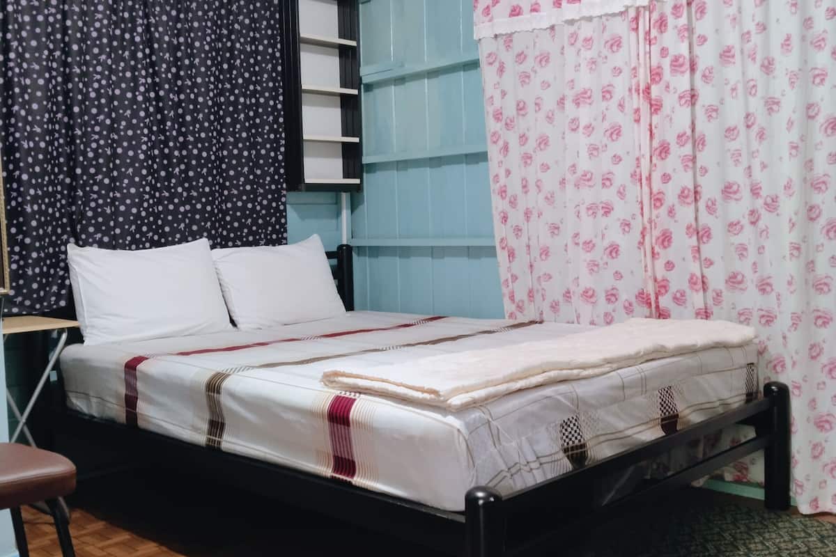 A single bed with a white mattress and a red and white striped blanket, a black metal frame, and a wooden floor.