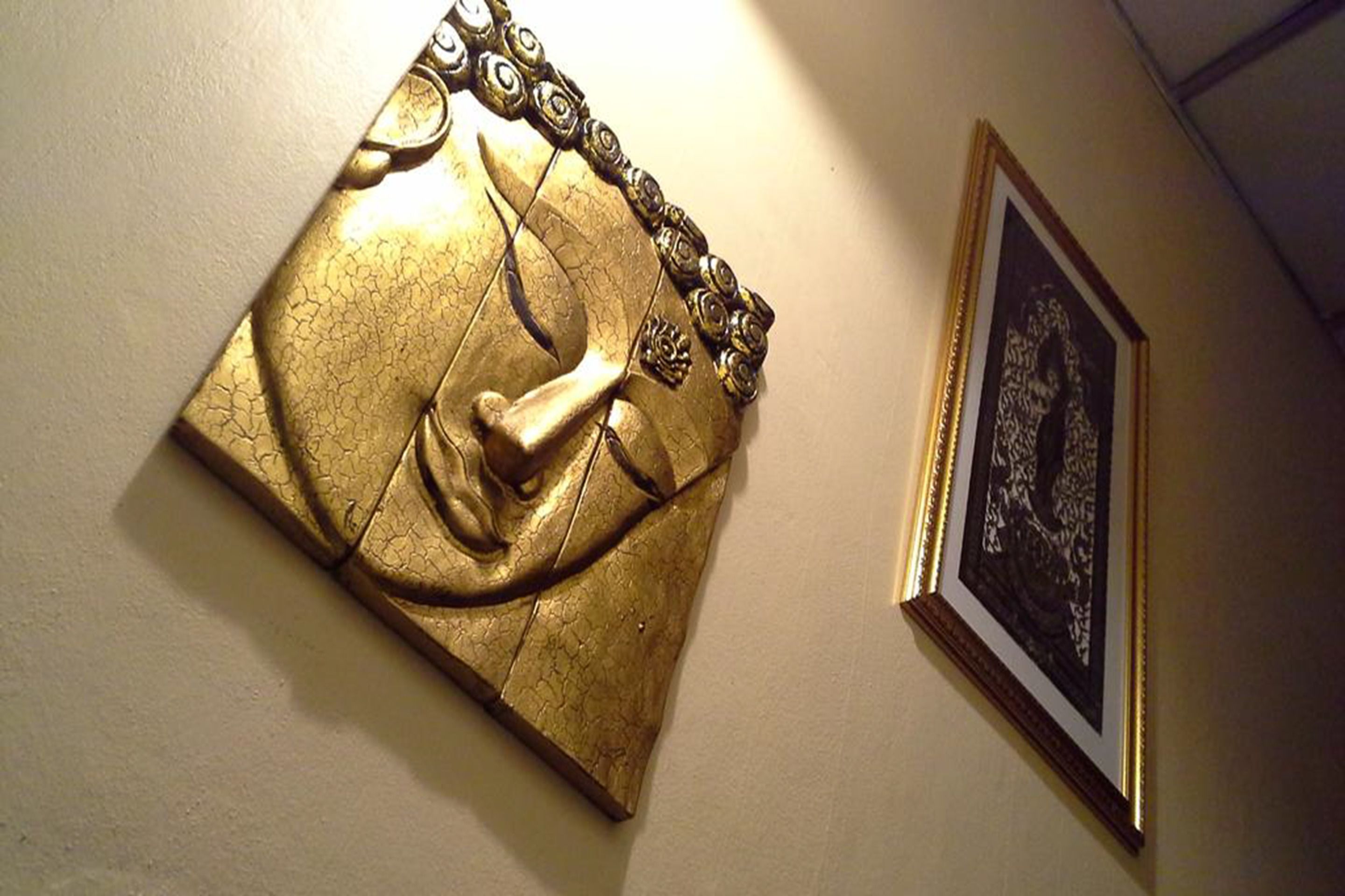 Een goudkleurig beeldhouwwerk met een kettingdetail aan een muur.