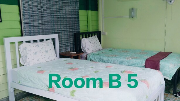 A room with two beds, a window with curtains, an air conditioner, and a fan. - Ban Kru Ae Homestay (Bangkok)