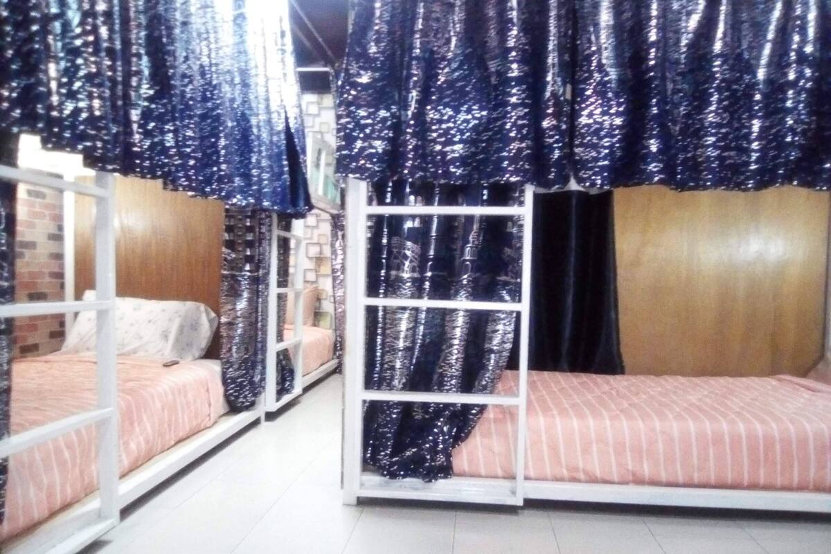 A room with bunk beds, each with a mattress and pillows. There is a ladder attached to the bunk beds.