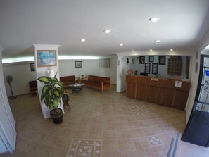 A reception area with a wooden desk, two sofas, a coffee table, and a potted plant.
