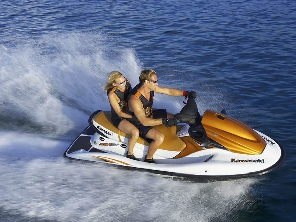 A person riding a white and orange jet ski on water.