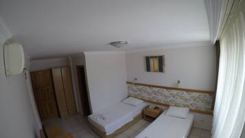 Habitación de hotel con dos camas, un armario de madera, una mesita de noche con teléfono y una ventana con cortinas.