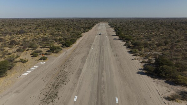 A long, straight road in a desert landscape with sparse vegetation.