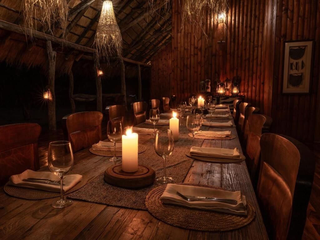 A long dining table set for a meal with candles, surrounded by chairs.