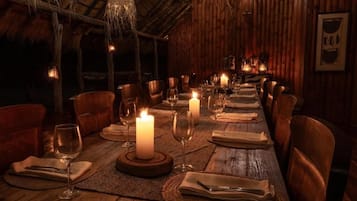 A long dining table set for a meal with candles, surrounded by chairs.
