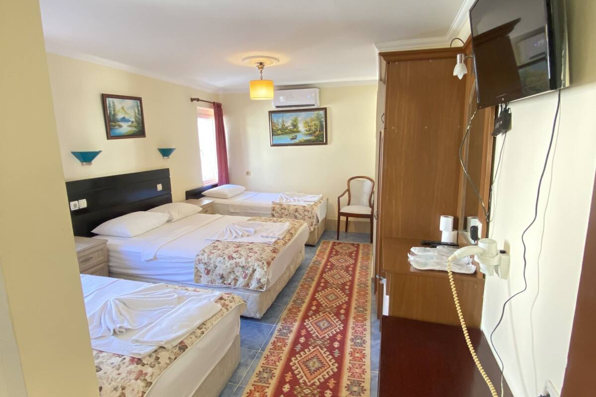 A hotel room with two beds, a wooden wardrobe, a television, and a telephone.