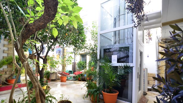 A courtyard with potted plants, a hammock, and a glass door leading to a building. - Sevin Hotel (Bodrum)