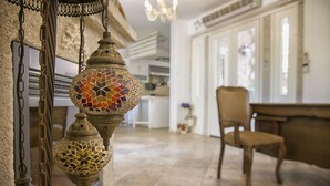 A room with a tiled floor, a wooden chair, and hanging decorative lamps. - Alya Ruzgari Otel (Cesme)