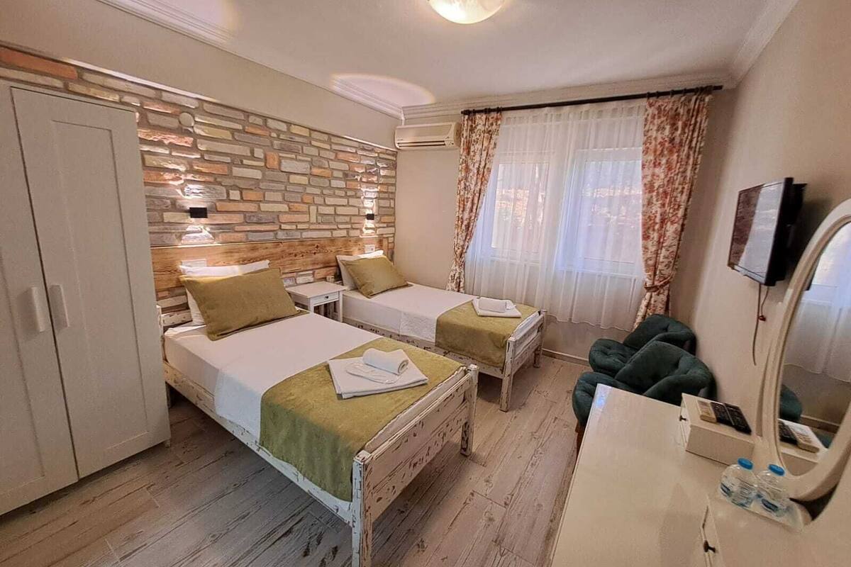 A hotel room with two beds, a wardrobe, a desk with a mirror, and a television.