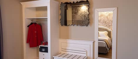 A bedroom with a white bed, a white bench, a wardrobe, and a mirror.