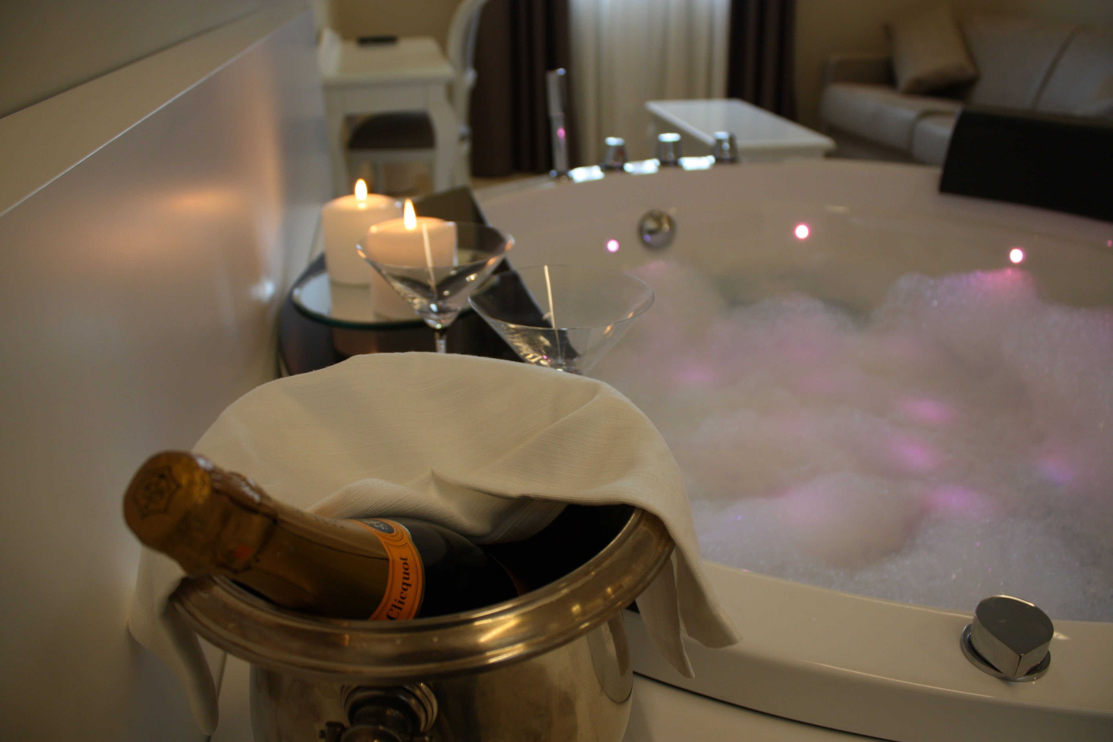 Un bain à remous, une bouteille de champagne, une bougie et un verre à martini.