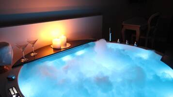 Un bain à remous avec des bougies et des verres disposés sur une table.