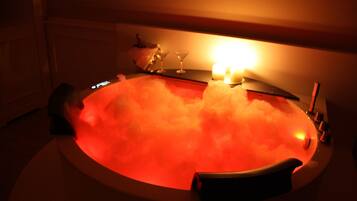 Uma banheira de hidromassagem com luz vermelha, um copo e uma vela.