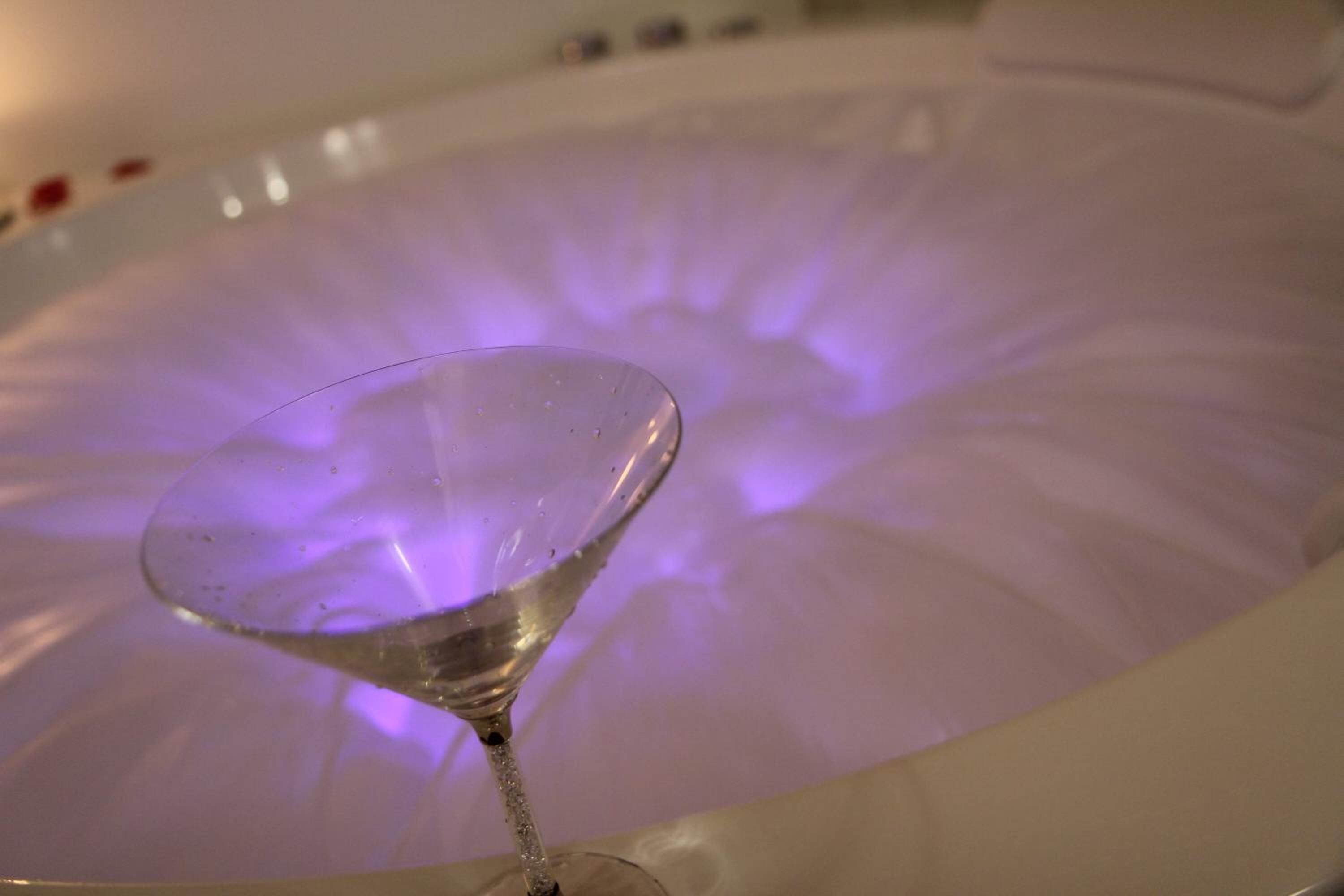 Un verre d’eau transparent dans une baignoire éclairée d’une lumière violette.