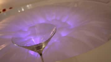 Un verre d’eau transparent dans une baignoire éclairée d’une lumière violette.