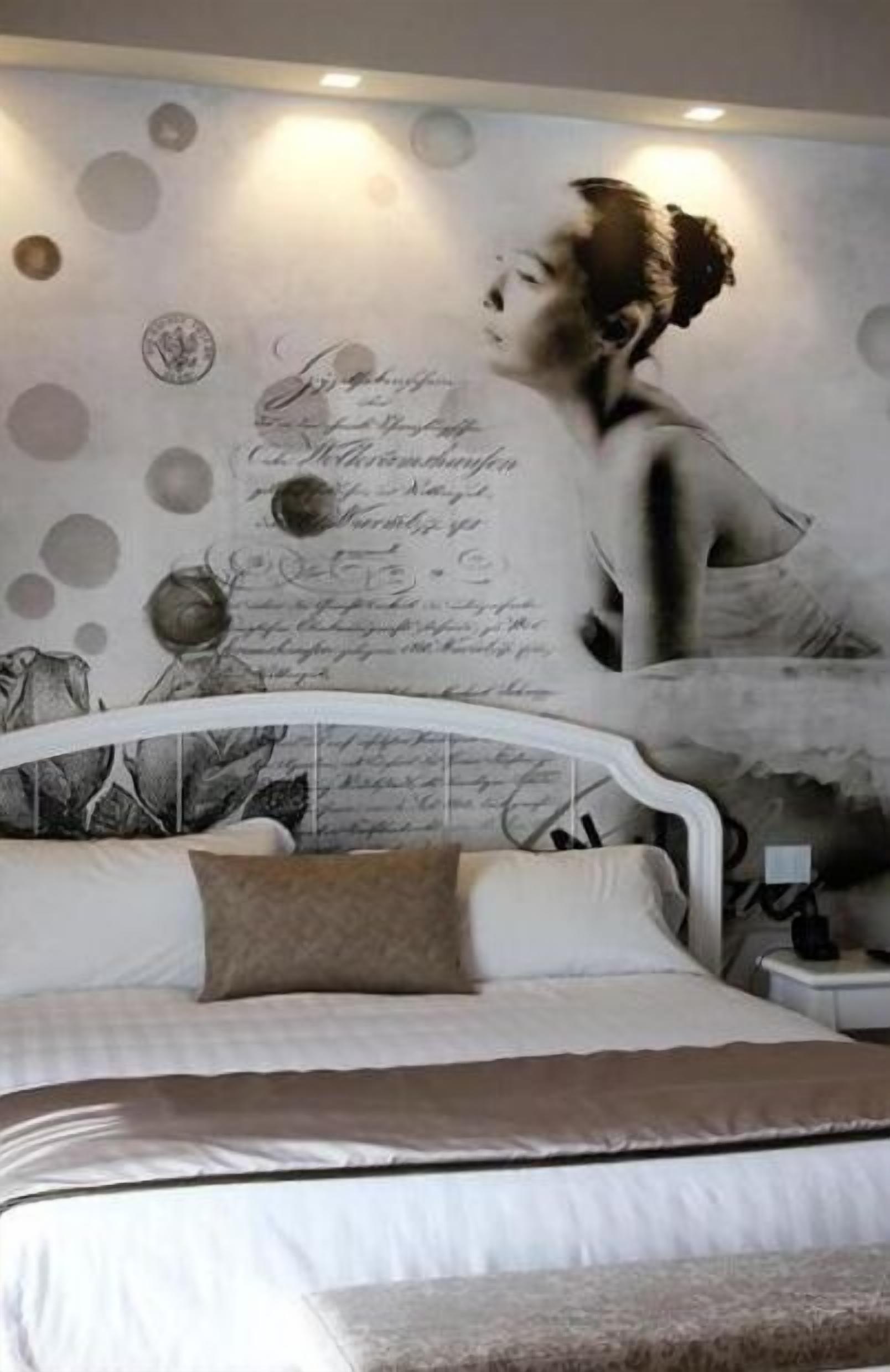 Un dormitori amb un llit, una nit i un mural a la paret.