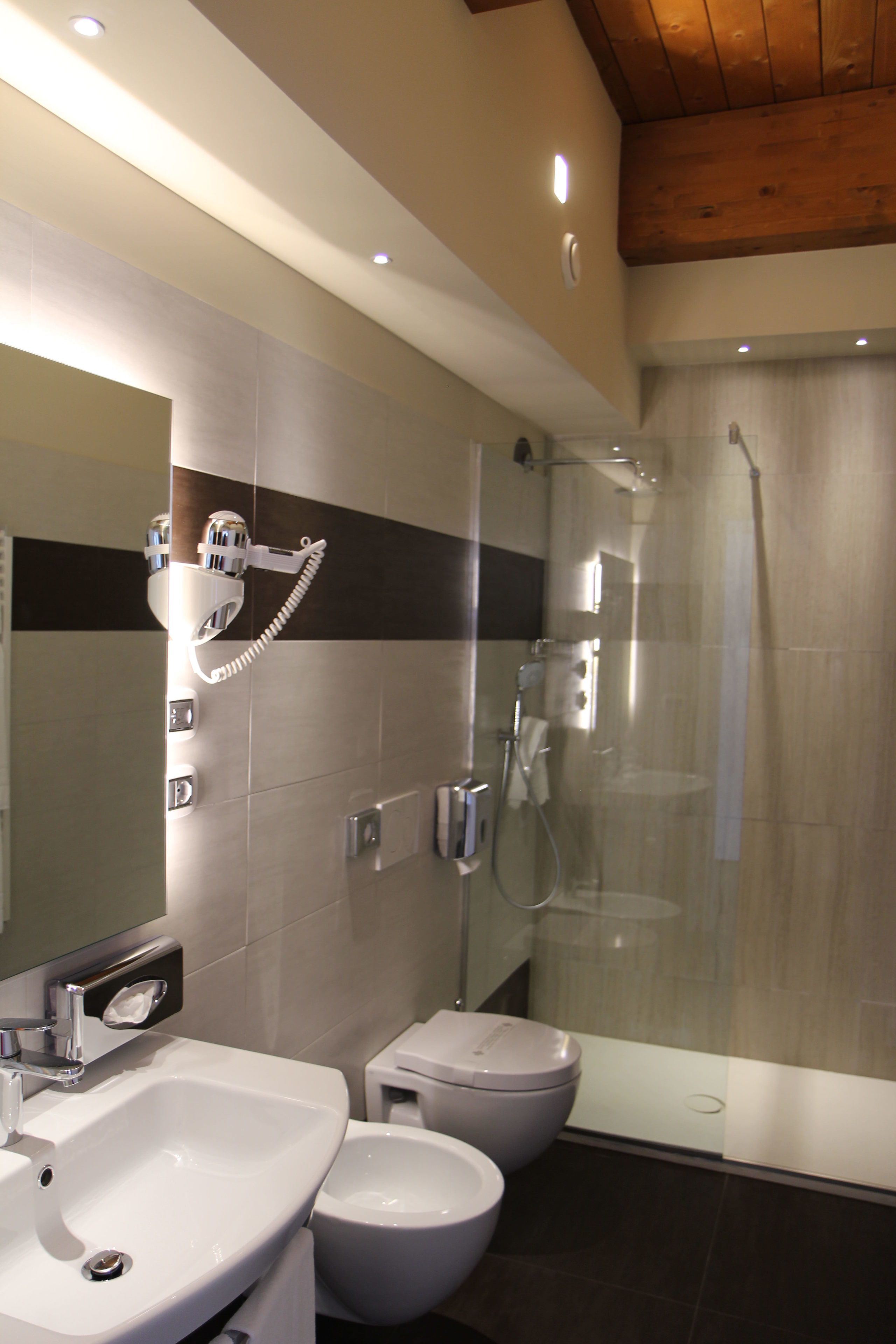 A modern bathroom with a glass-enclosed shower, a double sink, and a bidet.
