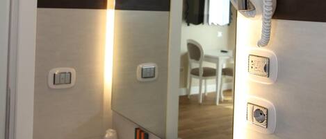 Une salle de bain moderne dotée d’un grand miroir, d’un lavabo encastré, d’un sèche-cheveux et d’un téléphone.