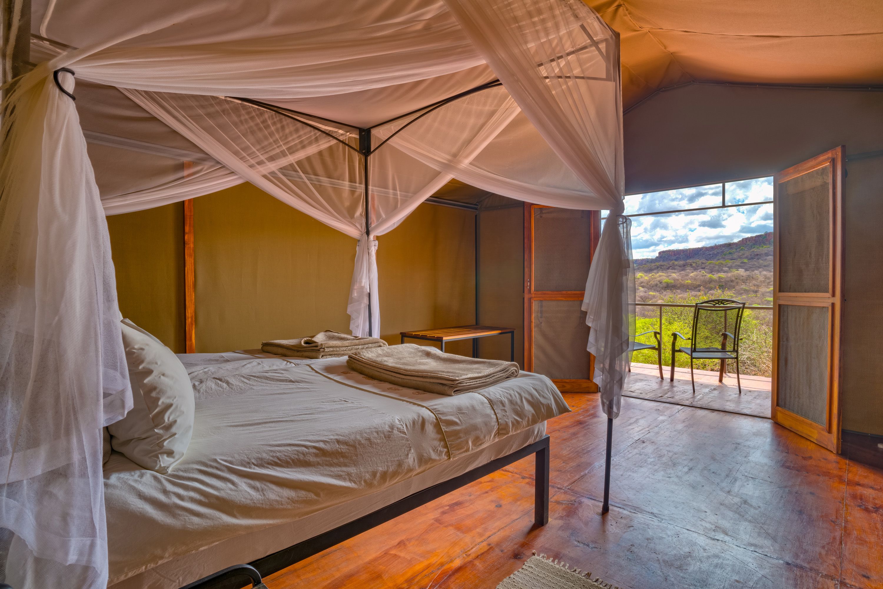 A bedroom with a bed, a table, and a view of the outdoors.