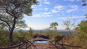 A hot tub with two lounge chairs, surrounded by natural landscape and a clear sky. - Waterberg Wilderness (Waterberg)