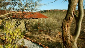 A house with a red roof, surrounded by a gravel path and sparse vegetation. - Waterberg Wilderness (Waterberg)