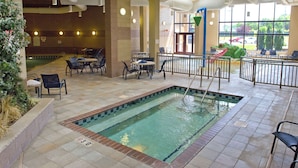 Zona interior de piscina con una pequeña piscina, asientos alrededor y vistas al exterior a través de amplios ventanales.